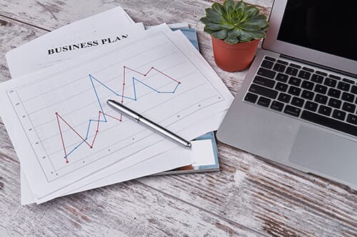 Business plans on a desk with a mac